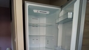 Un refrigerador abierto con múltiples estantes y un panel de control digital de temperatura.