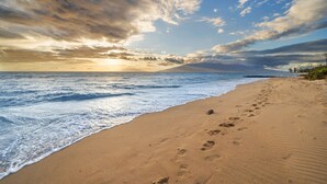 A beach with footprints and a dog on the sand, leading to the ocean. - Where Waves Sing South Maui Gated Oceanfront Home Hot Tub Private Oasis (Kihei)