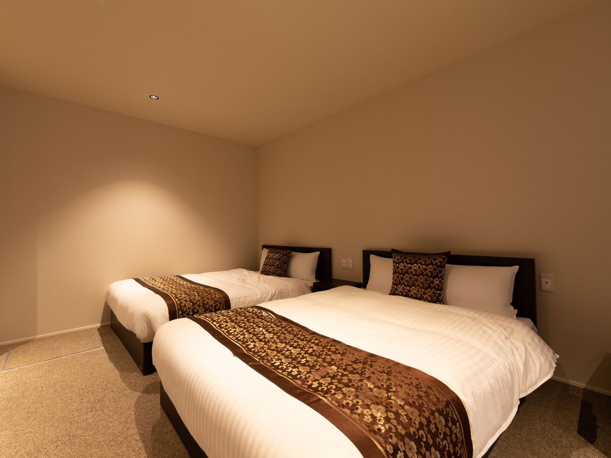 A hotel room with two beds, each with a patterned bedspread and matching pillows.