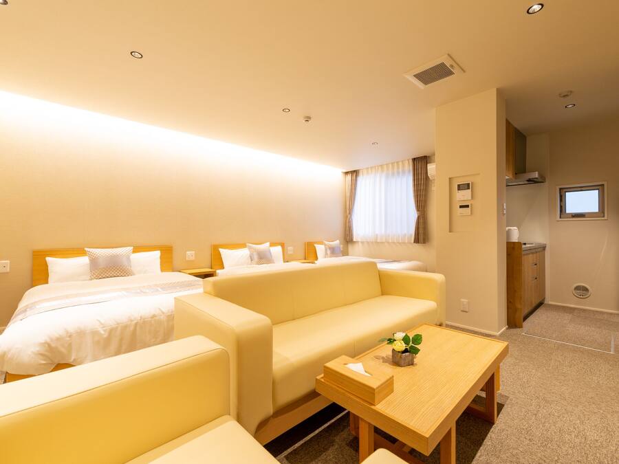 Een hotelkamer met twee bedden, een bank, een eettafeltje en een kitchenette.