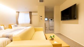 Une chambre d’hôtel comprenant un lit, un canapé, une télévision, une petite table et une kitchenette.