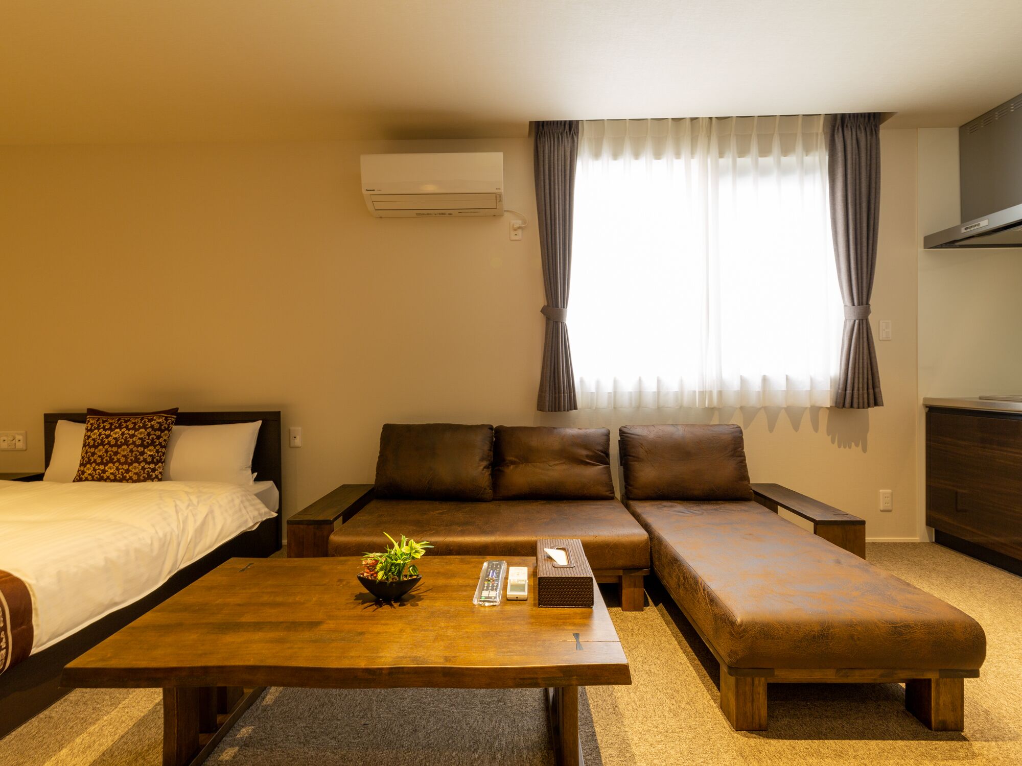 A hotel room with a bed, a sofa, a coffee table, and a TV.