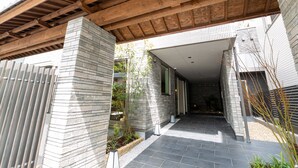Un edificio moderno con techo de madera y paredes de piedra, que incluye un sendero de piedra y un pequeño jardín.