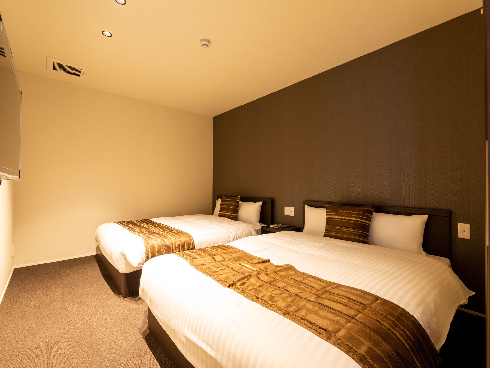 Ein Hotelzimmer mit zwei Betten, jeweils mit brauner Kopfteil und weißer Bettwäsche.