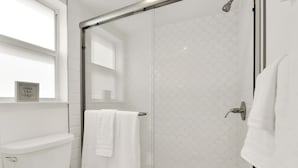 A modern bathroom with a glass shower enclosure, a toilet, and a towel rack. - Boutique Hotel Queen room w/ Bunk bed. POOL, LOCATION! Walk to BEACH/Restaurants (Deerfield Beach)