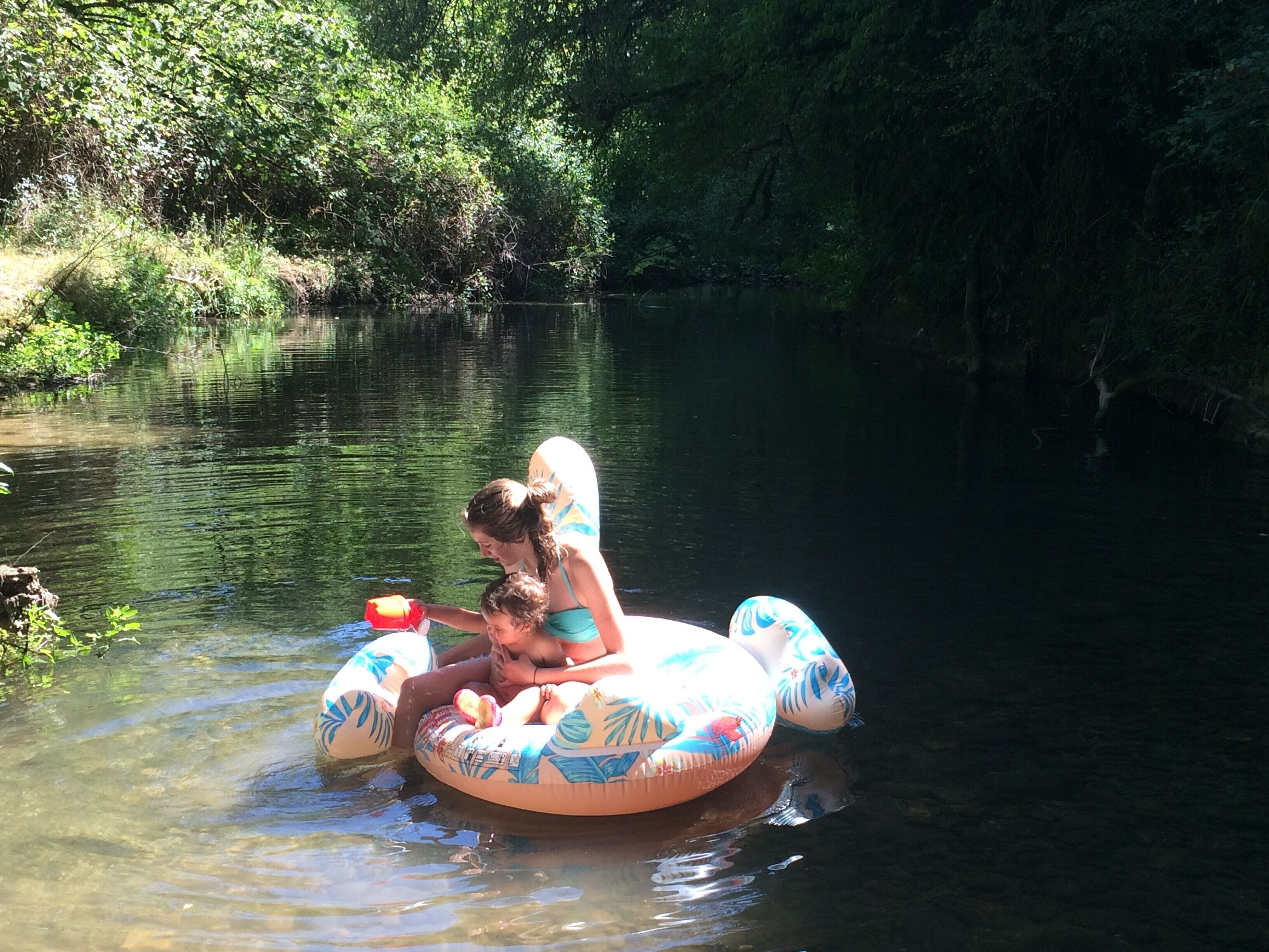 Une scène de rivière avec une femme et un enfant sur une bouée.