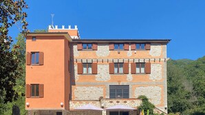 Un edificio de dos plantas con fachada de piedra y contraventanas de madera.