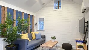 A modern living room with a blue sofa, wooden accents, a small table, and potted plants.