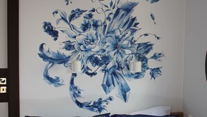 A bedroom with a bed, two pillows, and a wall with a floral mural.