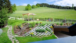 A garden with a wooden pergola, stone steps, and a fenced area with a bench and picnic table. - House Oberzöhr App 2 (Deutschnofen)