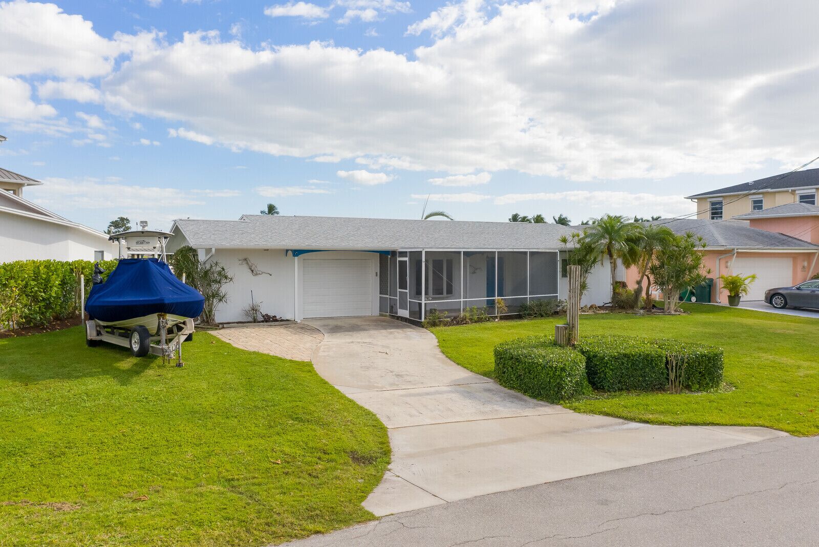A single-story house with a covered boat trailer, a garage, and a well-maintained lawn.