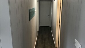 Een smalle gang met houten lambrisering en een deur aan het einde.