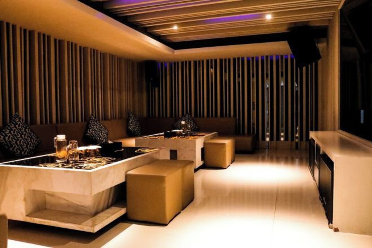 Un interior moderno con zona de bar, asientos acolchados y un diseño de pared con listones de madera.