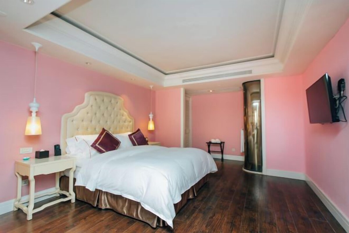 A bedroom with a large bed, bedside tables, and a TV on the wall.