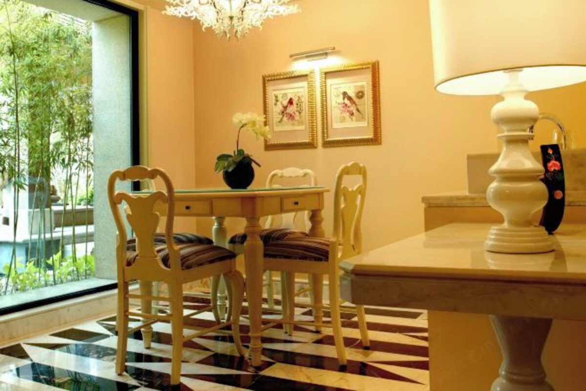 Un comedor con suelo a cuadros, una mesa con sillas, una araña y cuadros en la pared.