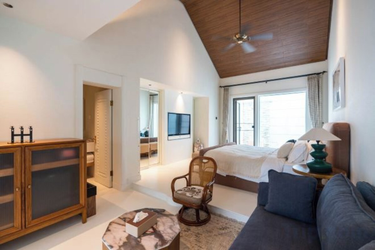 A bedroom with a bed, a sofa, a chair, a TV, and a cabinet.