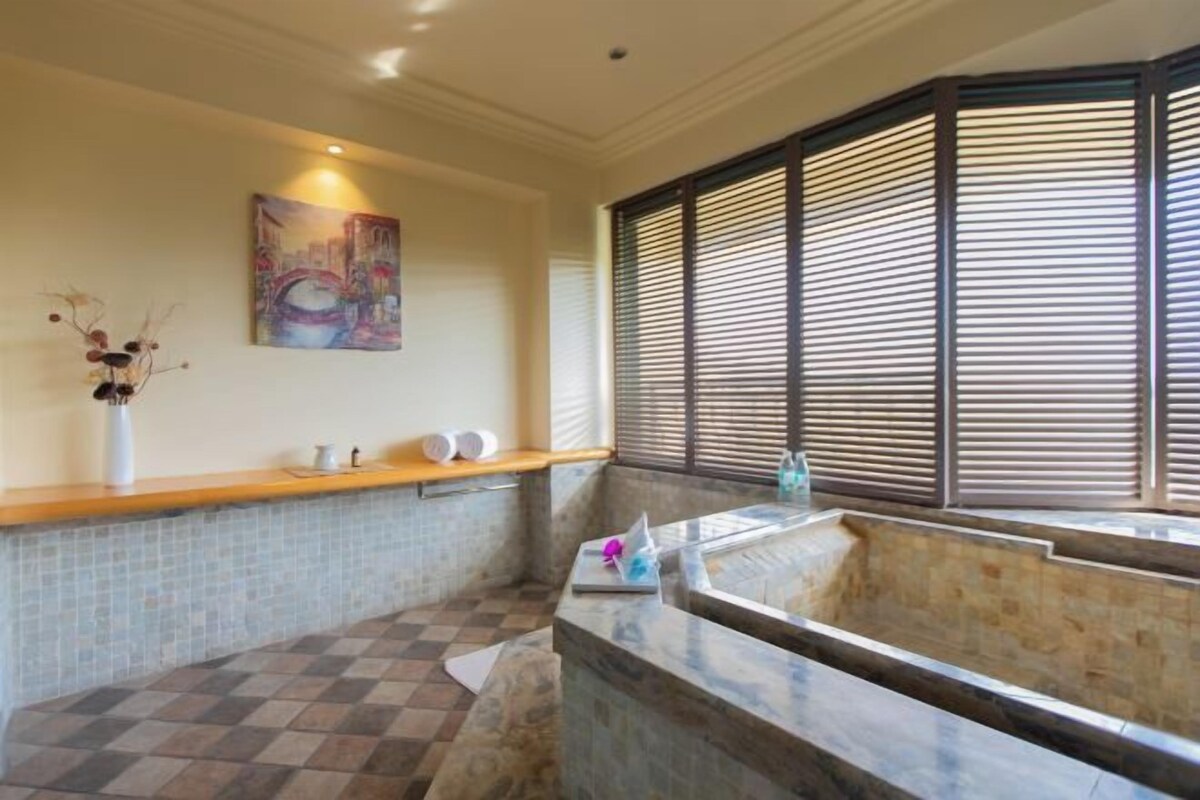 A bathroom with a checkered floor, a marble sink, a painting on the wall, and a window with blinds.