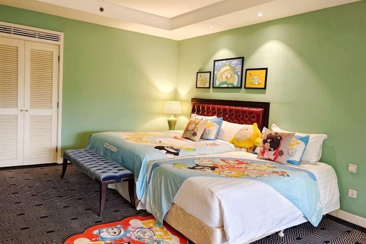 A bedroom with two beds, a bench, a door, and a wall with framed pictures.