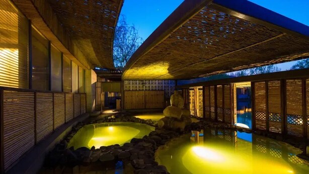 A traditional Japanese onsen with two hot spring pools, wooden walkways, and a bamboo ceiling. - Beijing Chunhuiyuan Hot Spring Resort Hotel (Beijing)