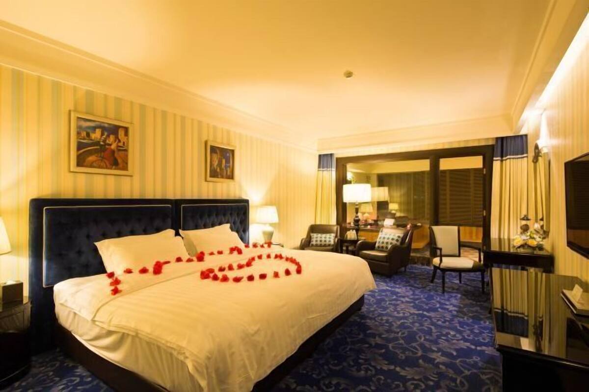 A hotel room with a large bed, a desk, a chair, and a television.