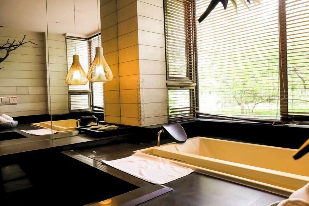 A modern bathroom with a large bathtub, a sink, and two pendant lights.