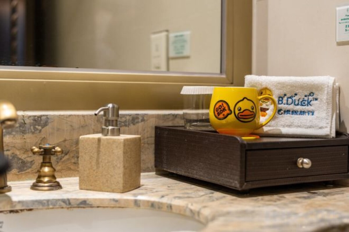 A bathroom with a marble countertop, a towel rack with a towel, and a yellow mug with a duck design.