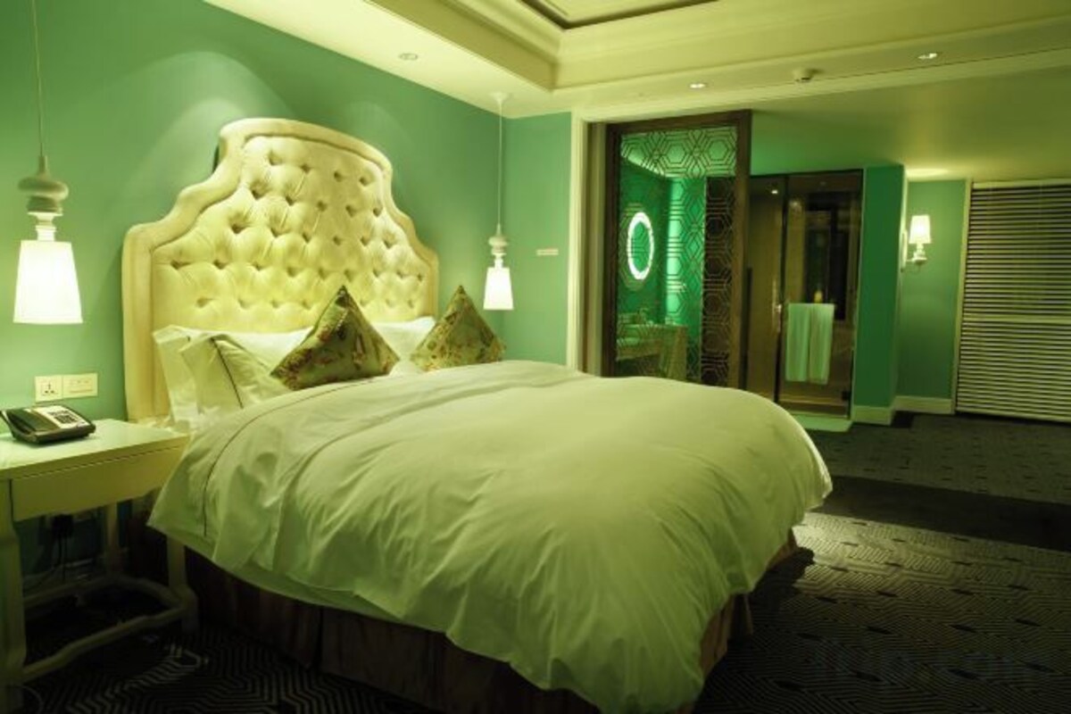 A hotel room with a large bed, a bedside table with a lamp, and a mirror.