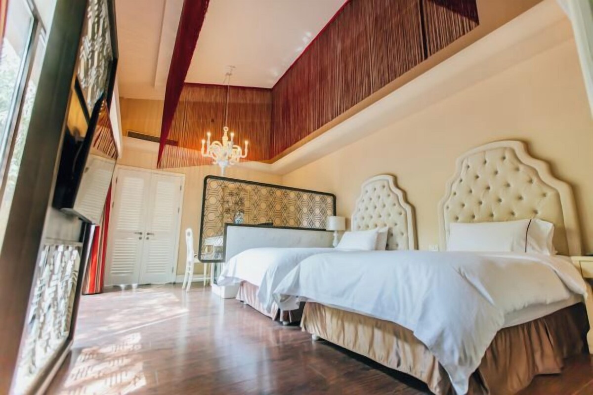 A bedroom with two beds, a chandelier, and a wooden ceiling.
