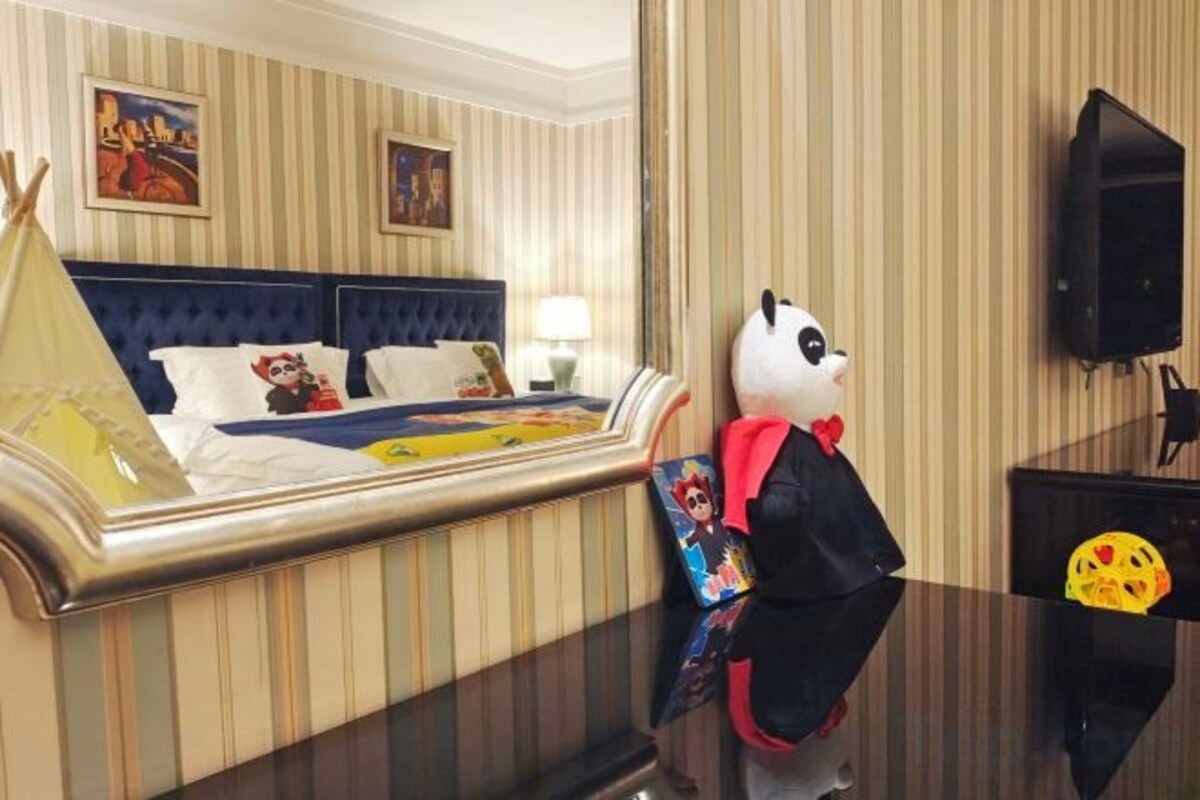 A hotel room with a bed, a television, and a decorative item resembling a panda.