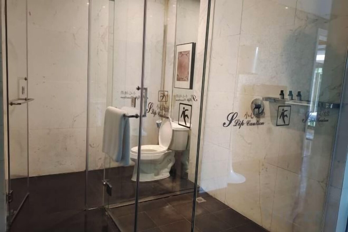 A glass-enclosed shower area with a toilet visible through the glass.