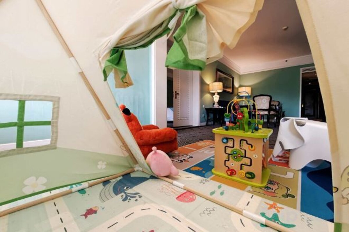A child's play area with a tent, a rocking chair, and a play table with toys.