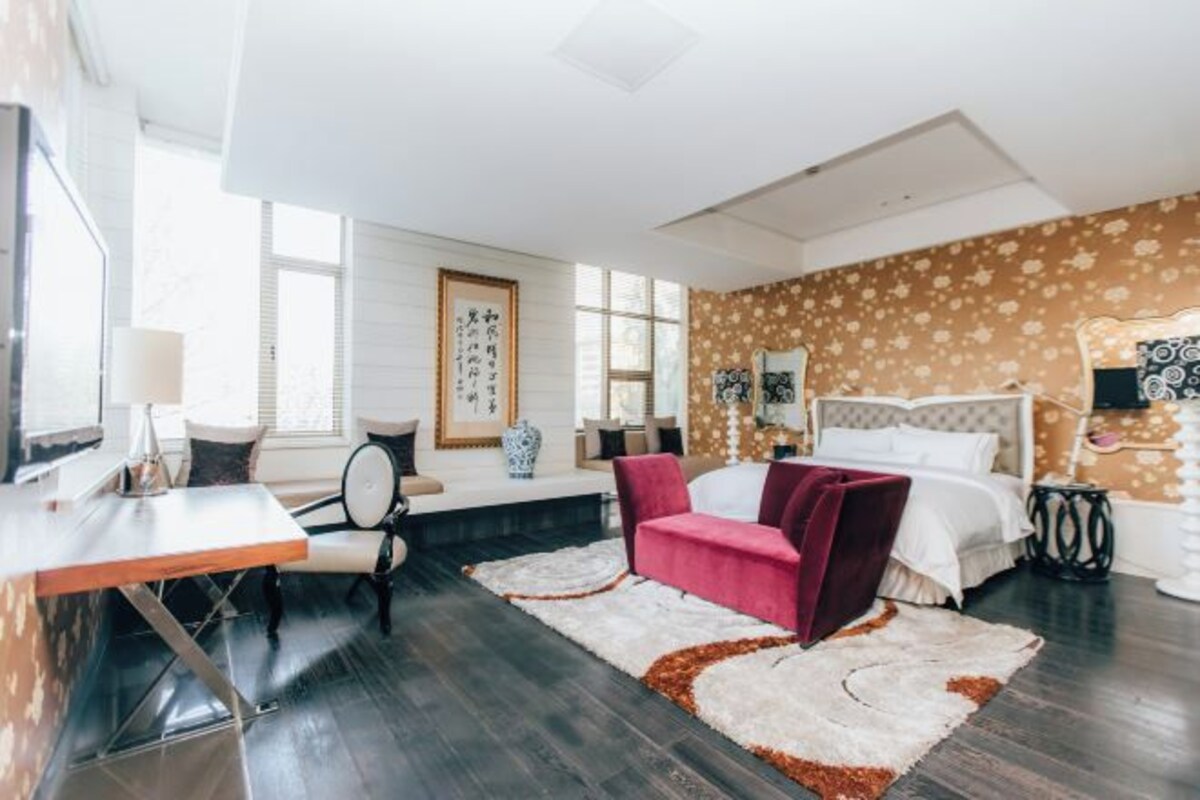 Una camera da letto moderna con un letto, una scrivania, una sedia e un divano rosso.