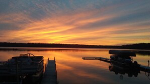 En rolig sø i solnedgang med både fortøjet ved en bro.