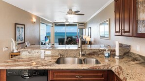 A kitchen with granite countertops, stainless steel sinks, and a Bosch dishwasher. - 🌊Kona Bali Kai #305 | Absolute Oceanfront | AC | Updated | Overlooking Banyans surf spot.🌊 (Kailua Kona)
