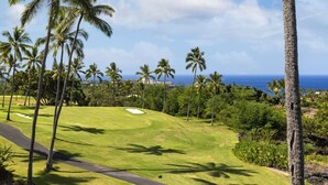 A golf course with palm trees, a clear sky, and a view of the ocean. - 🌊Kona Bali Kai #305 | Absolute Oceanfront | AC | Updated | Overlooking Banyans surf spot.🌊 (Kailua Kona)