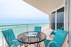 Ein Balkon mit rundem Tisch, Stühlen und Blick auf den Ozean.