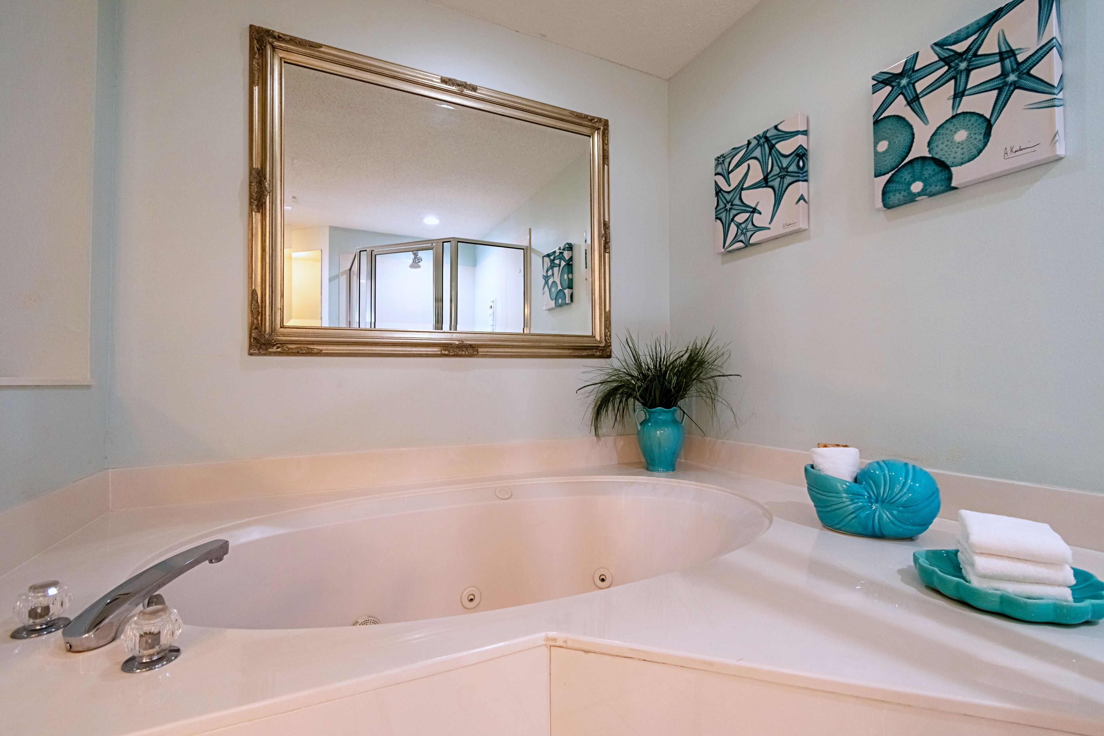 Ein Badezimmer mit einer großen Badewanne, einem Spiegel und zwei Wandbildern.