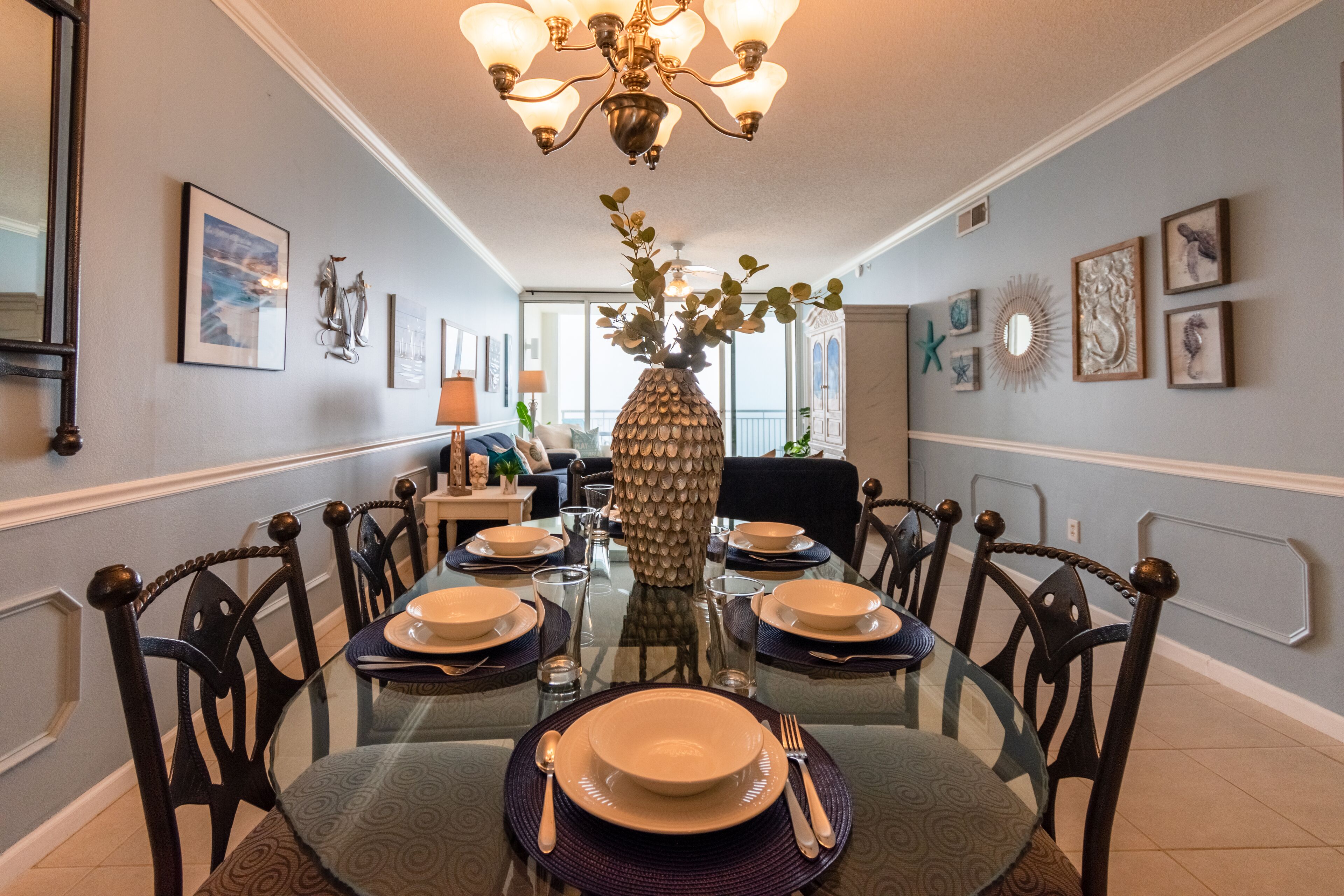 A dining room with a glass table set for six, surrounded by chairs.
