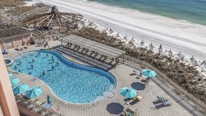 Une piscine sur le toit avec vue sur la plage, des chaises longues, des parasols et un toboggan.