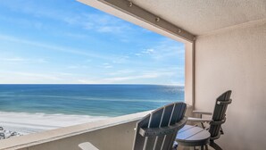 Un balcon avec deux fauteuils Adirondack donnant sur une plage et offrant une vue sur l’océan.
