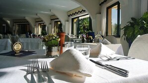 A dining table set with white tablecloth, silverware, and a decorative napkin.