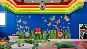 Un vibrante cuarto de juegos infantil con paredes coloridas, una bola de discoteca y diversas estructuras de juego.