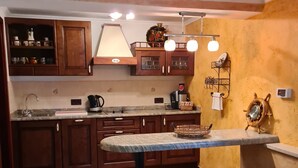 A kitchen with wooden cabinets, a marble countertop, and a bar area with stools. - Viktorov Comfortable 2-bed Apartment (Medulin)