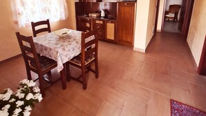 A dining area with a table and chairs, a kitchen with cabinets and a microwave, and a hallway leading to another room. - Viktorov Comfortable 2-bed Apartment (Medulin)