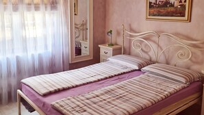A bedroom with a bed, a nightstand, a mirror, a painting, and a window with curtains. - Viktorov Comfortable 2-bed Apartment (Medulin)