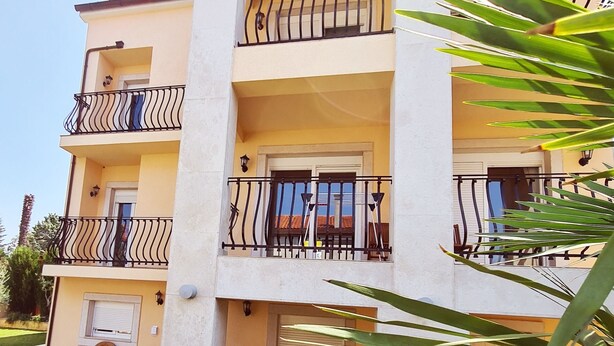 A multi-story building with balconies, a grassy lawn, and outdoor furniture. - Viktorov Comfortable 2-bed Apartment (Medulin)