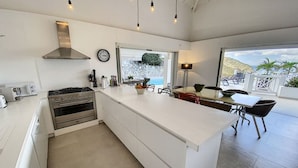 A modern kitchen with a large island, stainless steel appliances, and a view of the ocean. - Villa Casa Sand, luxury, 5 min walk from Anse Marcel beach (Anse Marcel)