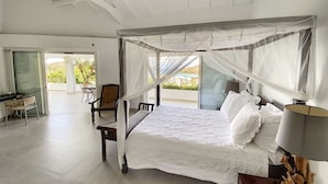 A spacious bedroom with a four-poster bed, a desk, and a chair, featuring a large window and a ceiling fan. - Villa Casa Sand, luxury, 5 min walk from Anse Marcel beach (Anse Marcel)