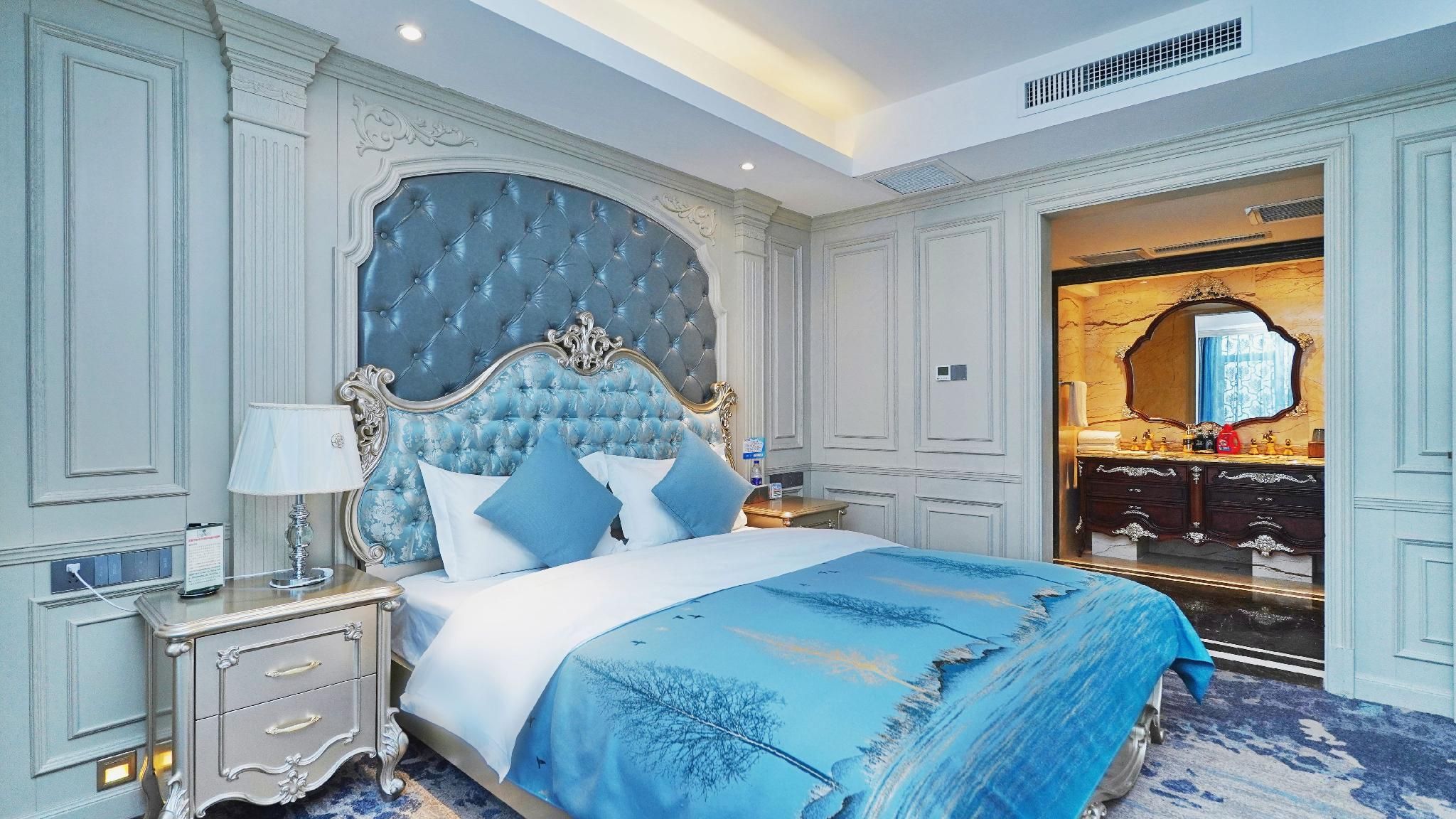 A bedroom with a large bed, a nightstand, a dresser, and a mirror.