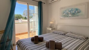 A hotel room with a bed, a nightstand, a painting, and a view of the outside. - Mediterraneo 20E by Casasol (Nerja)